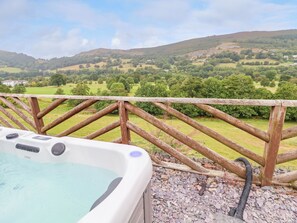 A hot tub with a view of rolling hills and a wooden fence. - The Willows (Llangollen)