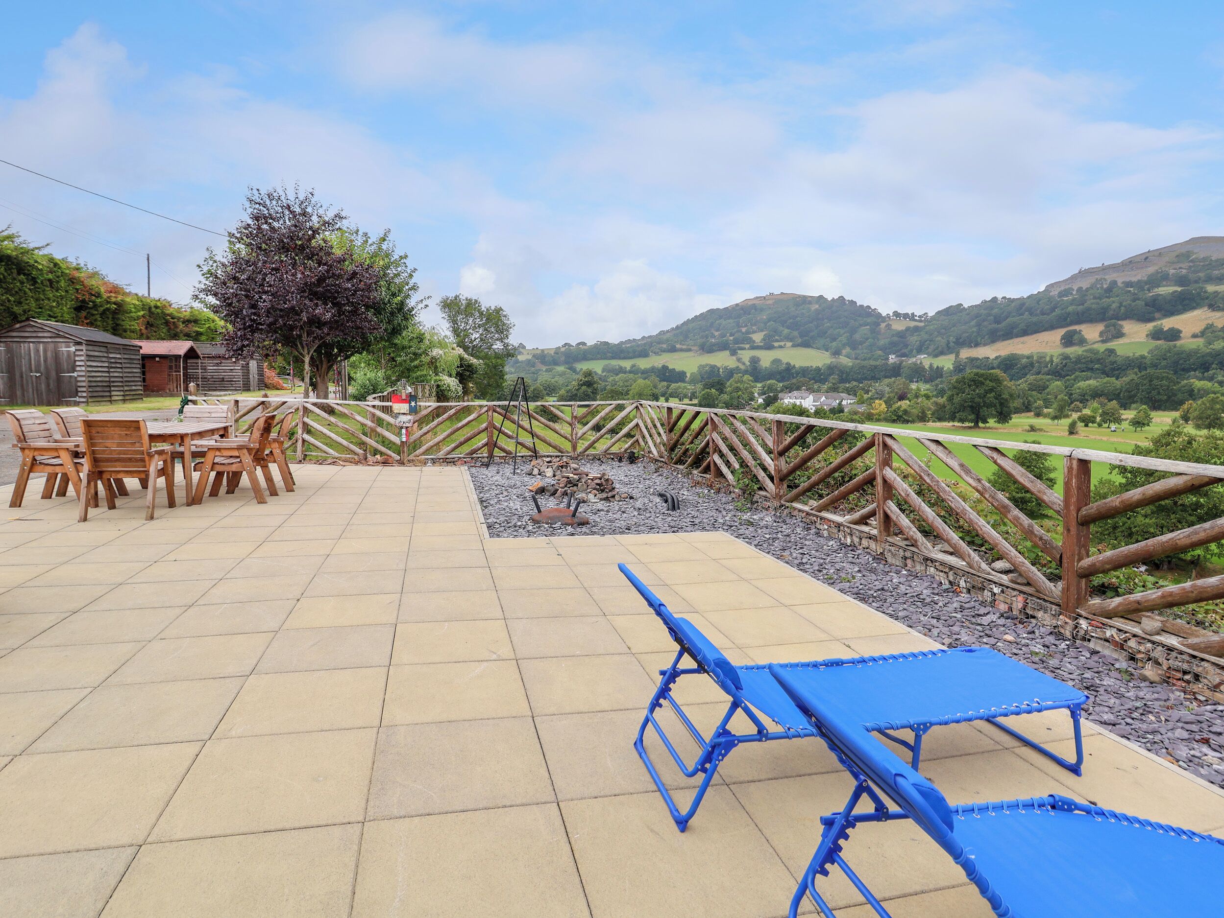 Un patio con mesa y sillas, una mesa azul, y vista al campo.
