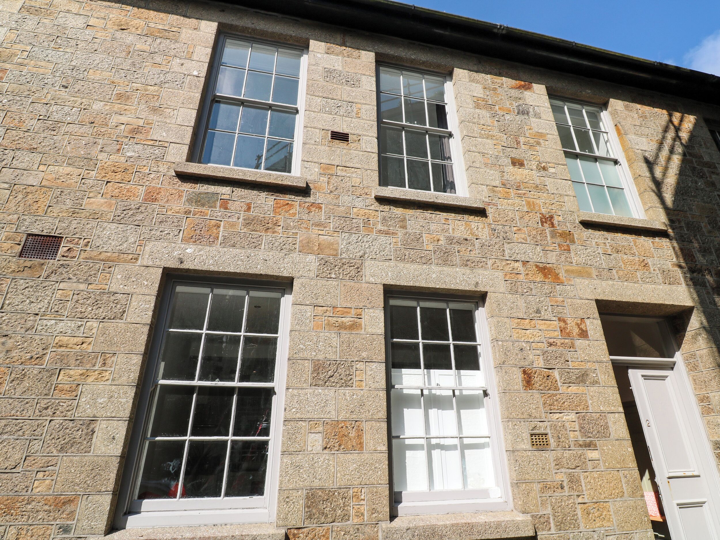 A stone building with three windows and a door.
