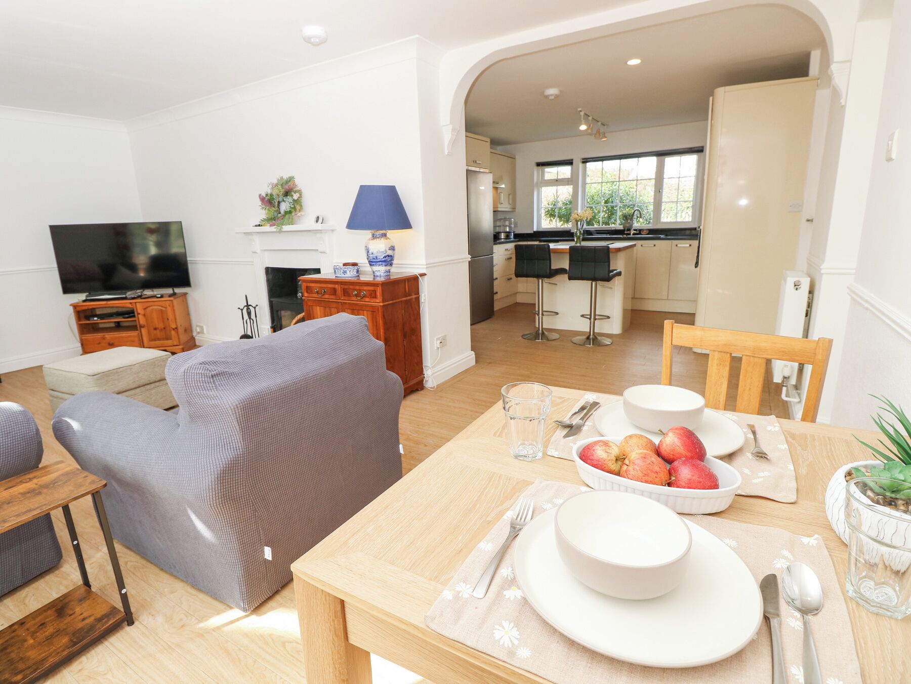A modern living room with a sofa, TV, and dining area with a table set for two.