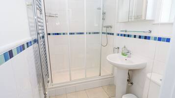 A bathroom with a glass-enclosed shower, a sink with a mirror above, and a toilet.