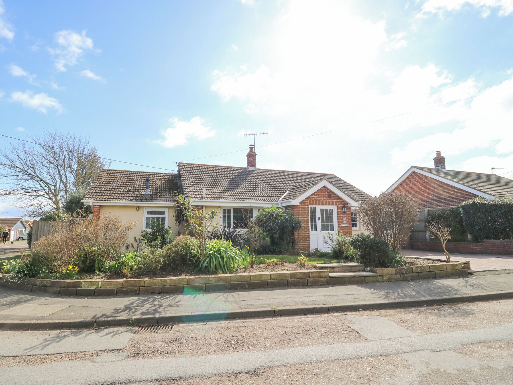 A row of two-story houses with a front garden, a visible chimney, and a clear sky.