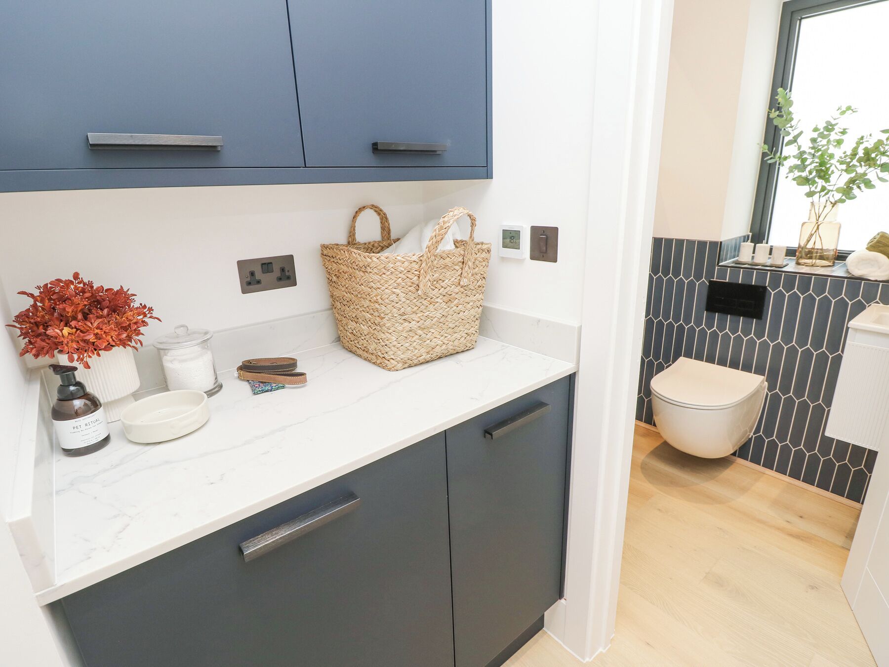 A modern kitchen with dark cabinets, a white countertop, and a wicker basket.