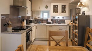 Une cuisine de taille réduite avec des meubles blancs, un four à micro-ondes, une cuisinière et un évier.
