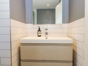 A bathroom with a white sink, a mirror above it, and a bottle of hand soap. - 7 Daltons Place (Arundel)