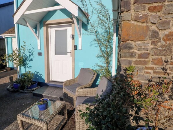 A cozy outdoor seating area with wicker furniture and potted plants. - The Hollybush (Kilgetty)