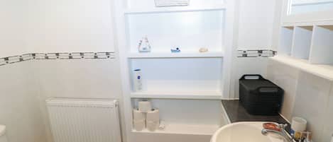Een badkamer met toilet, wastafel en planken met toiletartikelen.