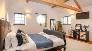 A bedroom with a bed, bedside table, dresser, and a TV mounted on the wall. - The Wing (Wrexham)