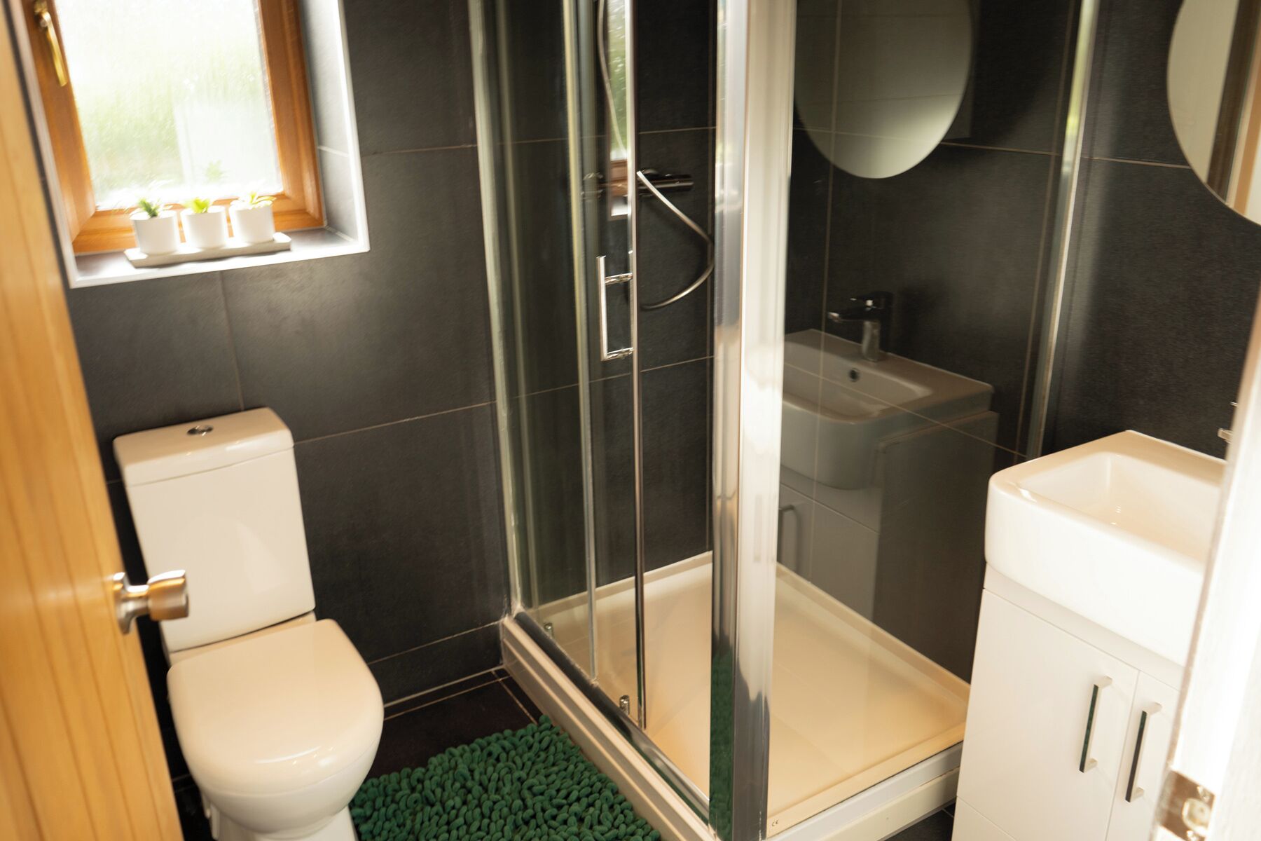 A modern bathroom with a glass-enclosed shower, a toilet, and a sink.