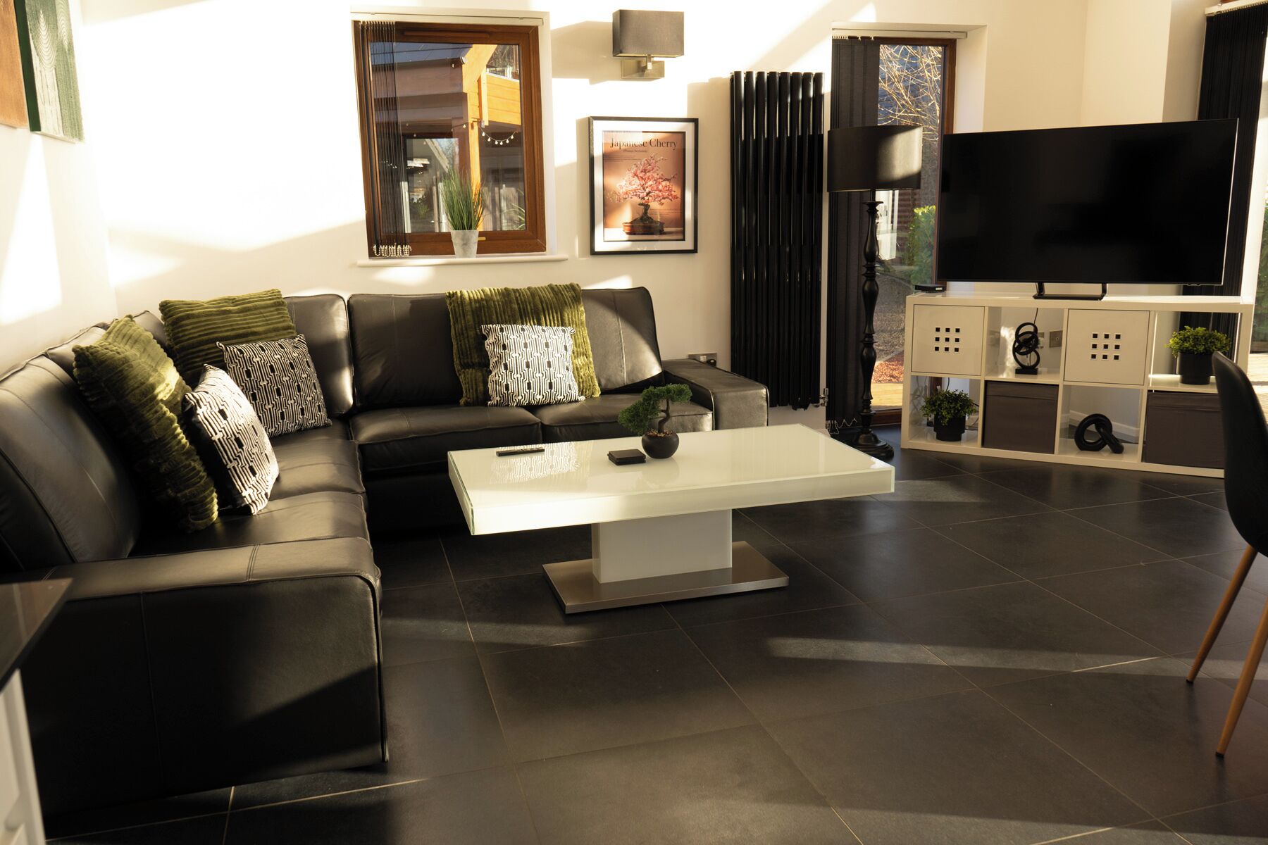 Un salon moderne avec un canapé en cuir noir, une table basse blanche et un téléviseur à écran plat.