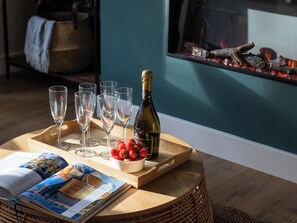 A wooden tray with a bottle of champagne, a bowl of strawberries, and several glasses on a round table. - Hebog (Caernarfon)