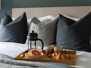 A neatly made breakfast tray on a bed with a coffee maker, two mugs, a bowl of fruit, and croissants. - Hebog (Caernarfon)