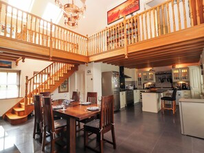 A spacious kitchen with wooden cabinets, a dining area with a wooden table and chairs, and a staircase connecting two levels. - Johnson's Cottage (Brandon)