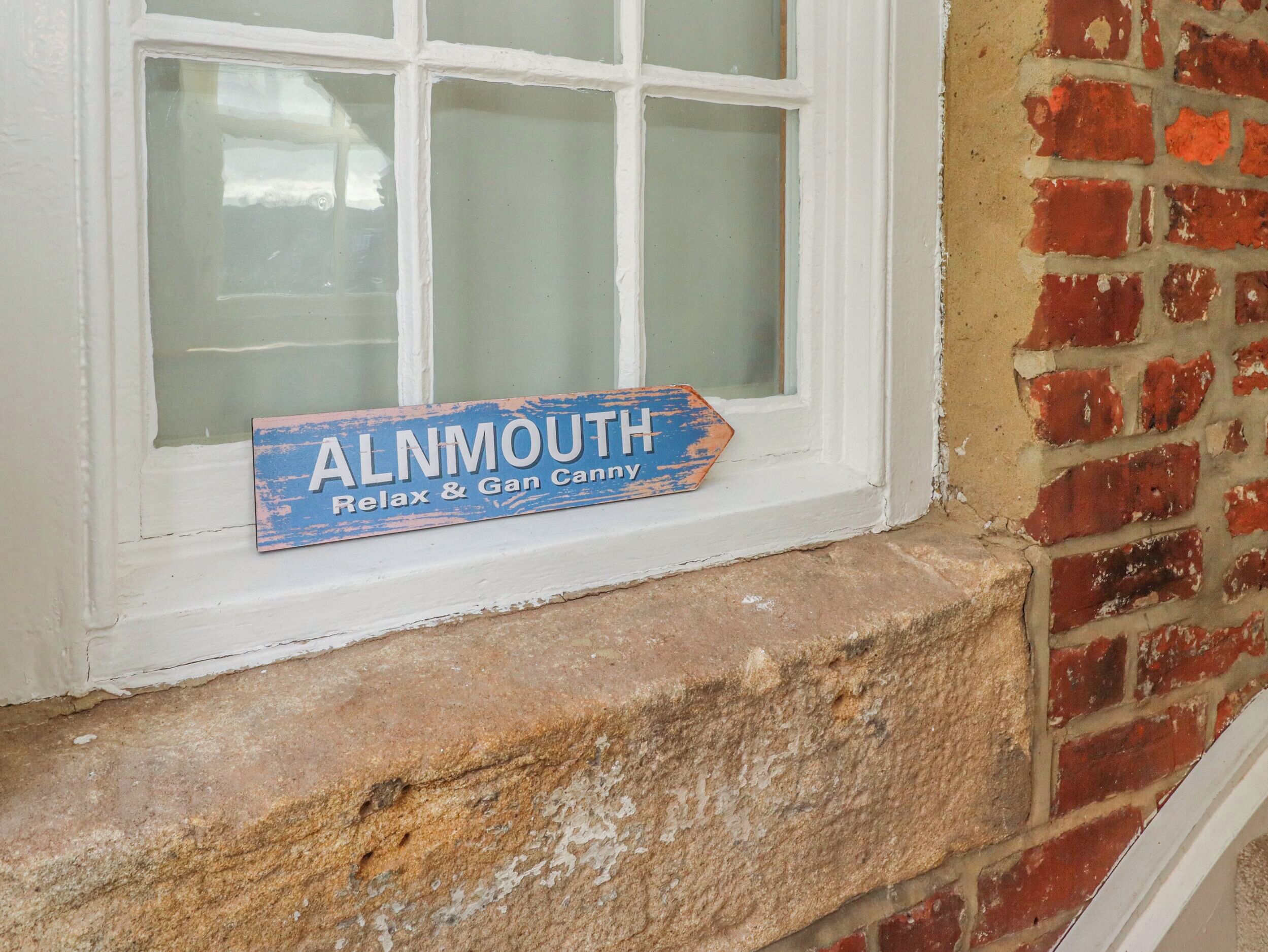 A window with a sign that reads "ALNMOUTH Relax & Gan Canny."