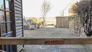 A wooden gate with a sign reading "SEAFIELD" leading to a gravel driveway. - Seafield Granary (Alnwick)