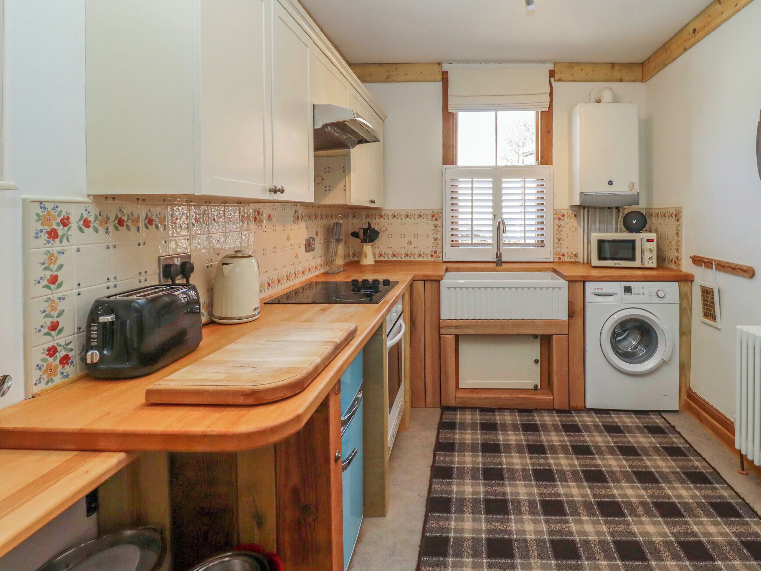 A compact kitchen with a toaster, kettle, microwave, and washing machine.