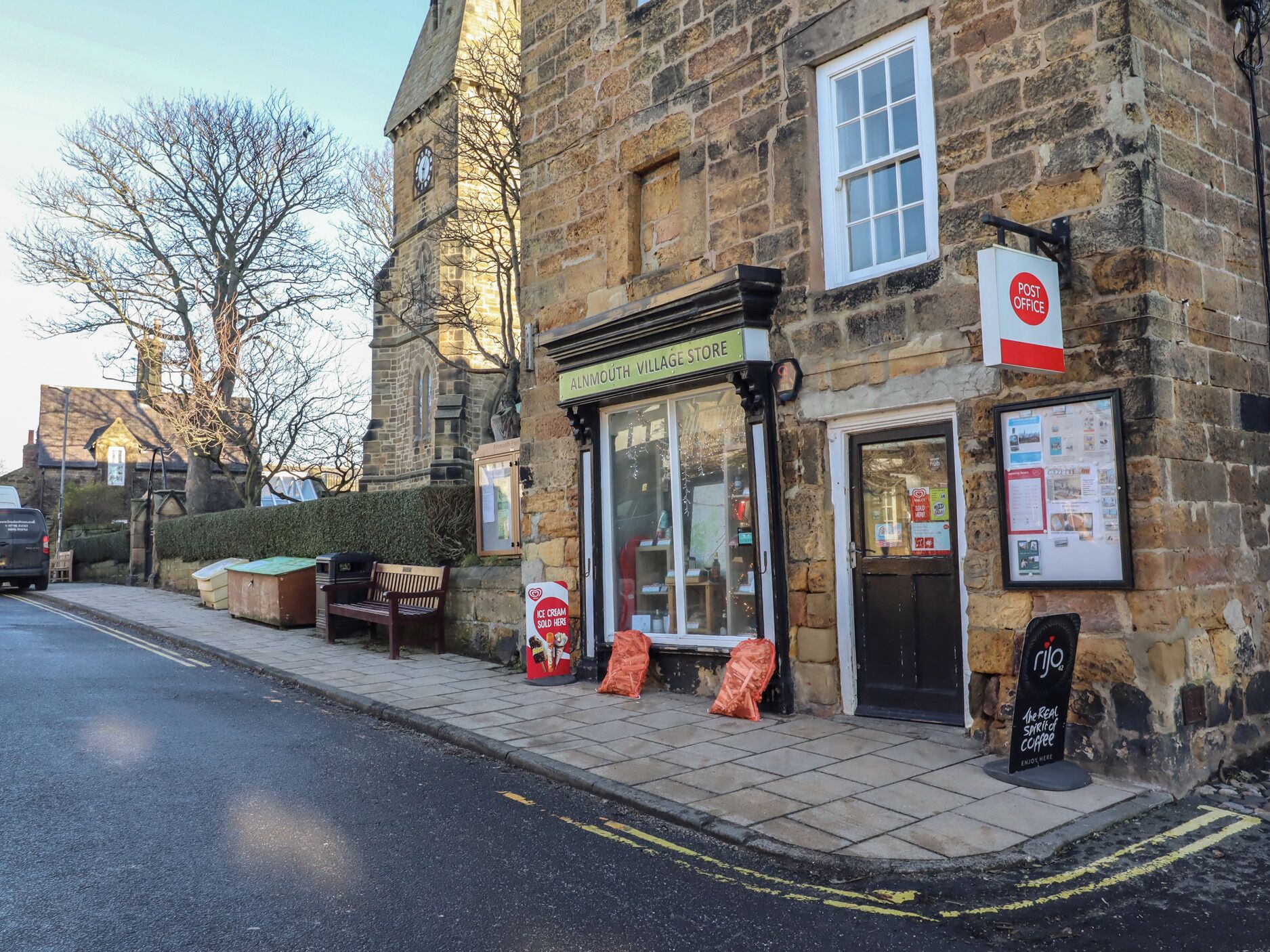 Un bâtiment en pierre avec une enseigne indiquant « Alnmouth Village Store » et une autre indiquant « Bureau de poste ».