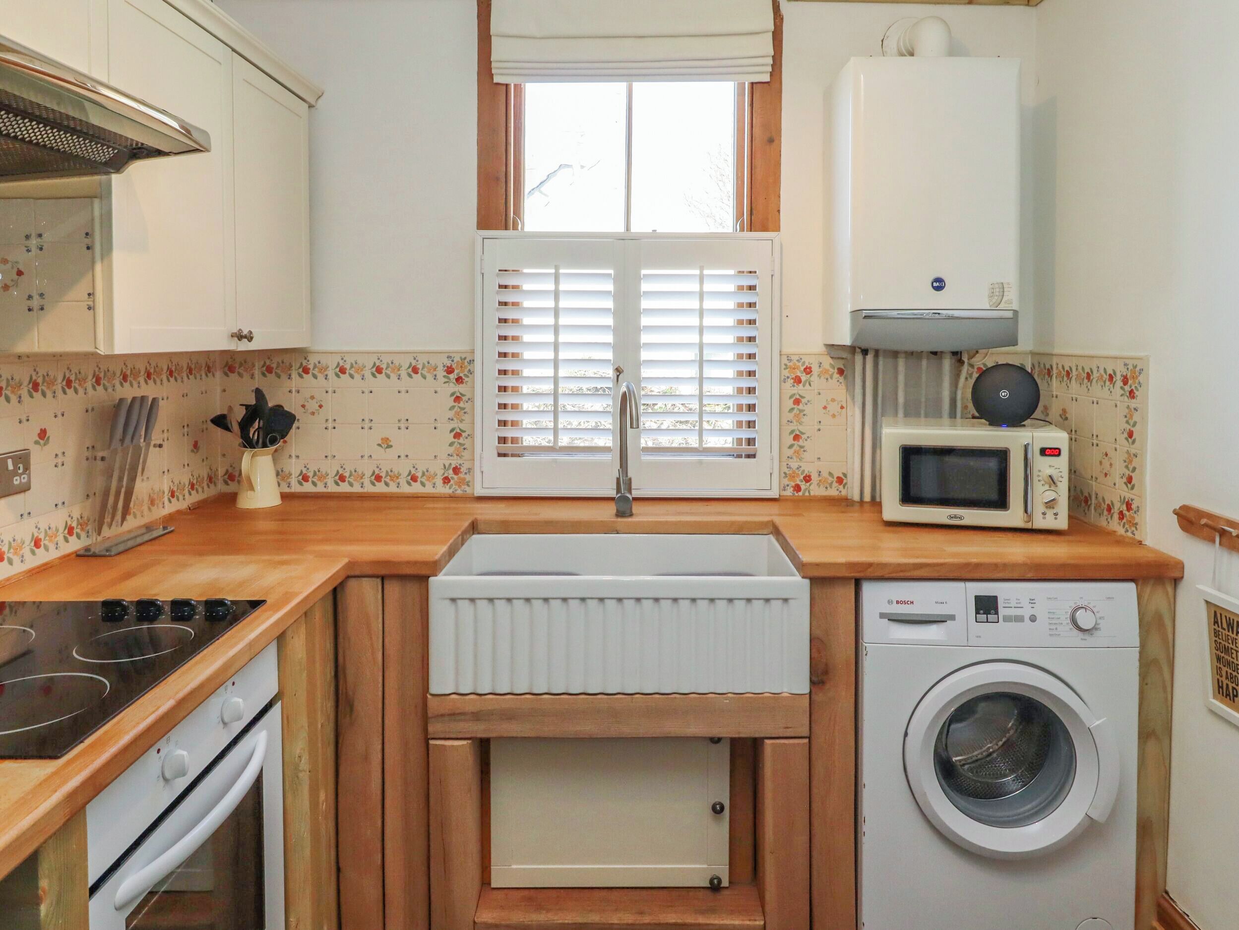 A compact kitchen with a stove, microwave, and washing machine.