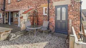 A brick building with a stone staircase, a door labeled "SeaField Grange," and a table with chairs outside. - Seafield Granary (Alnwick)