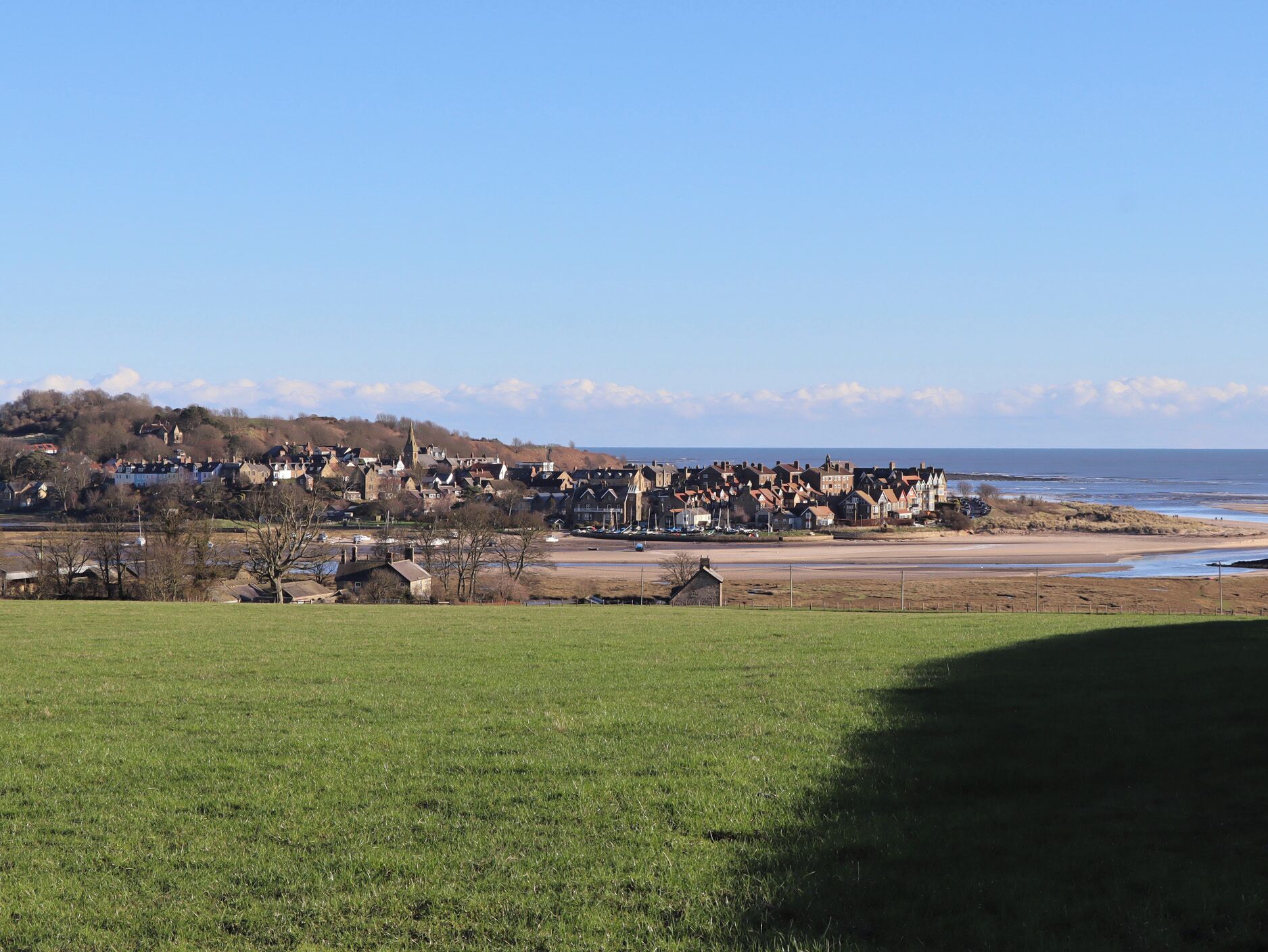 Une ville côtière où se côtoient des immeubles résidentiels et de vastes champs ouverts.