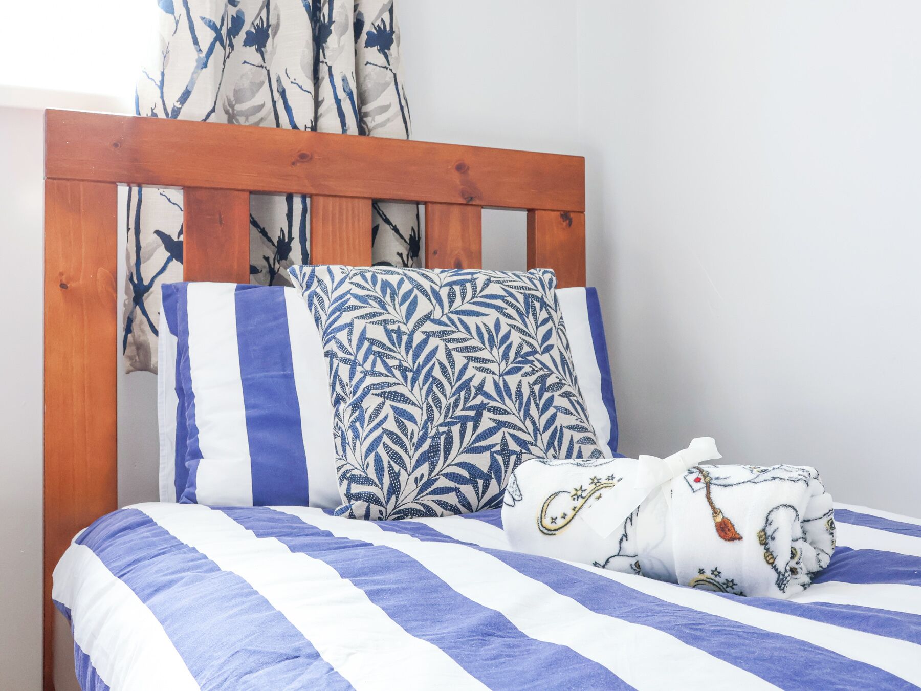A bed with a wooden headboard, striped bedding, and decorative pillows.