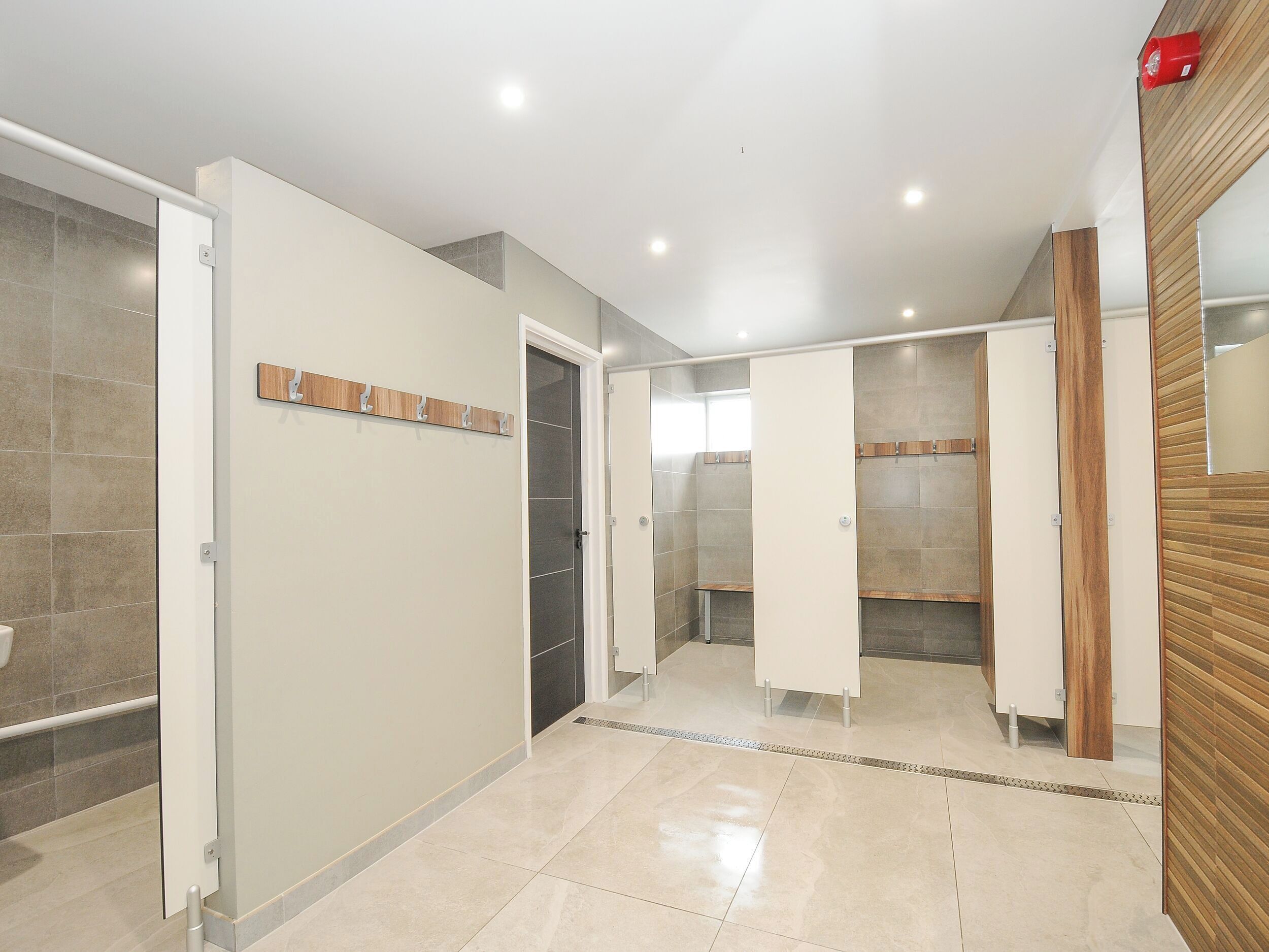 Un baño moderno con cabina de ducha, tocador con espejo y suelo de baldosas.