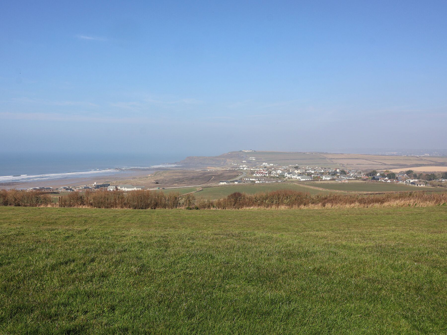 Un paysage côtier avec un village et des champs ouverts.