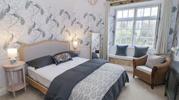 Une chambre à coucher avec un grand lit, une table de chevet, une chaise, une fenêtre avec des rideaux et un mur en pierre.
