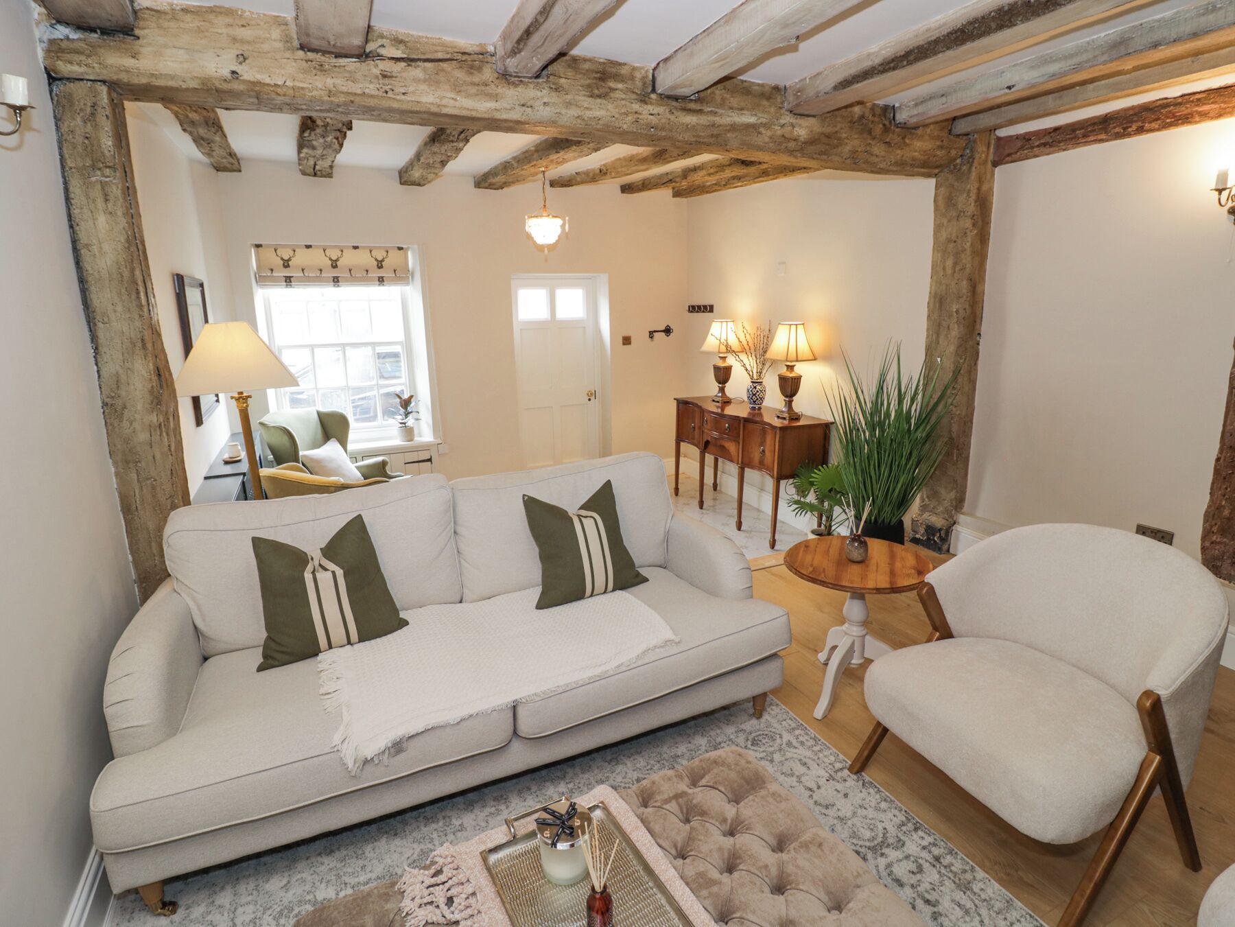 Una sala acogedora con un sofá, un sillón y una mesita de noche con lámparas.