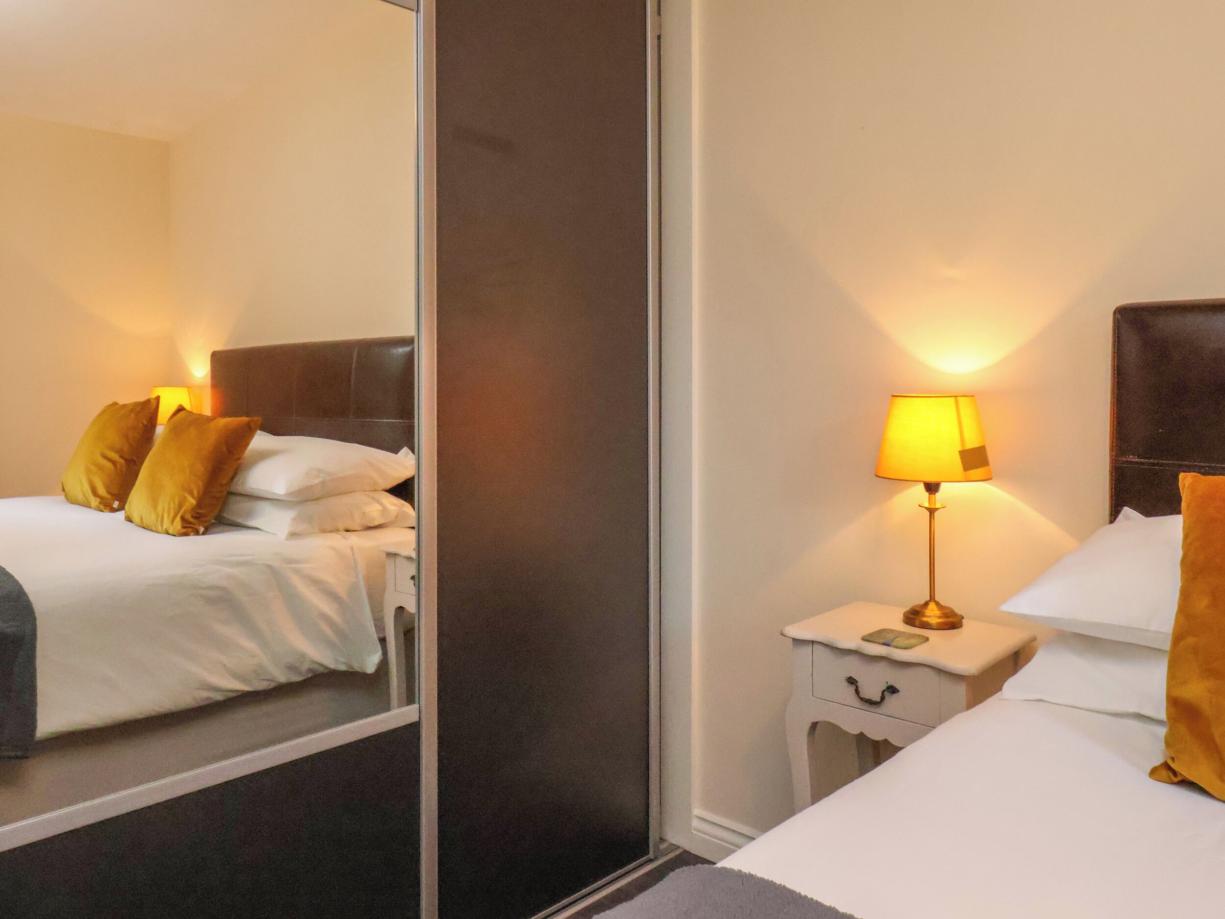 Ein Hotelzimmer mit Bett, Nachttisch, Lampe und Spiegel.