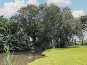 A serene riverside view with lush greenery and a grassy area. - Cowslip (Saltburn-by-the-Sea)