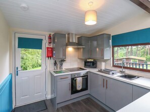 A compact kitchen with grey cabinets, a microwave, a stove, and a sink.