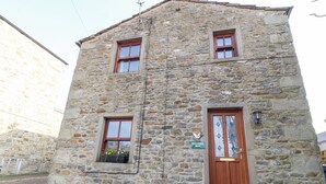 A stone building with a wooden door and two windows, one with a flower box. - Mallards Nest (Skipton)