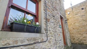 A stone building with a window displaying flowers. - Mallards Nest (Skipton)