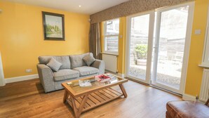 A living room with a grey sofa, a wooden coffee table, and a brown ottoman. - The Suite (Thornhill)