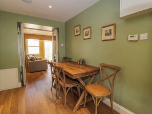 A dining area with a wooden table and chairs, a sofa, and a view into a living room. - The Suite (Thornhill)