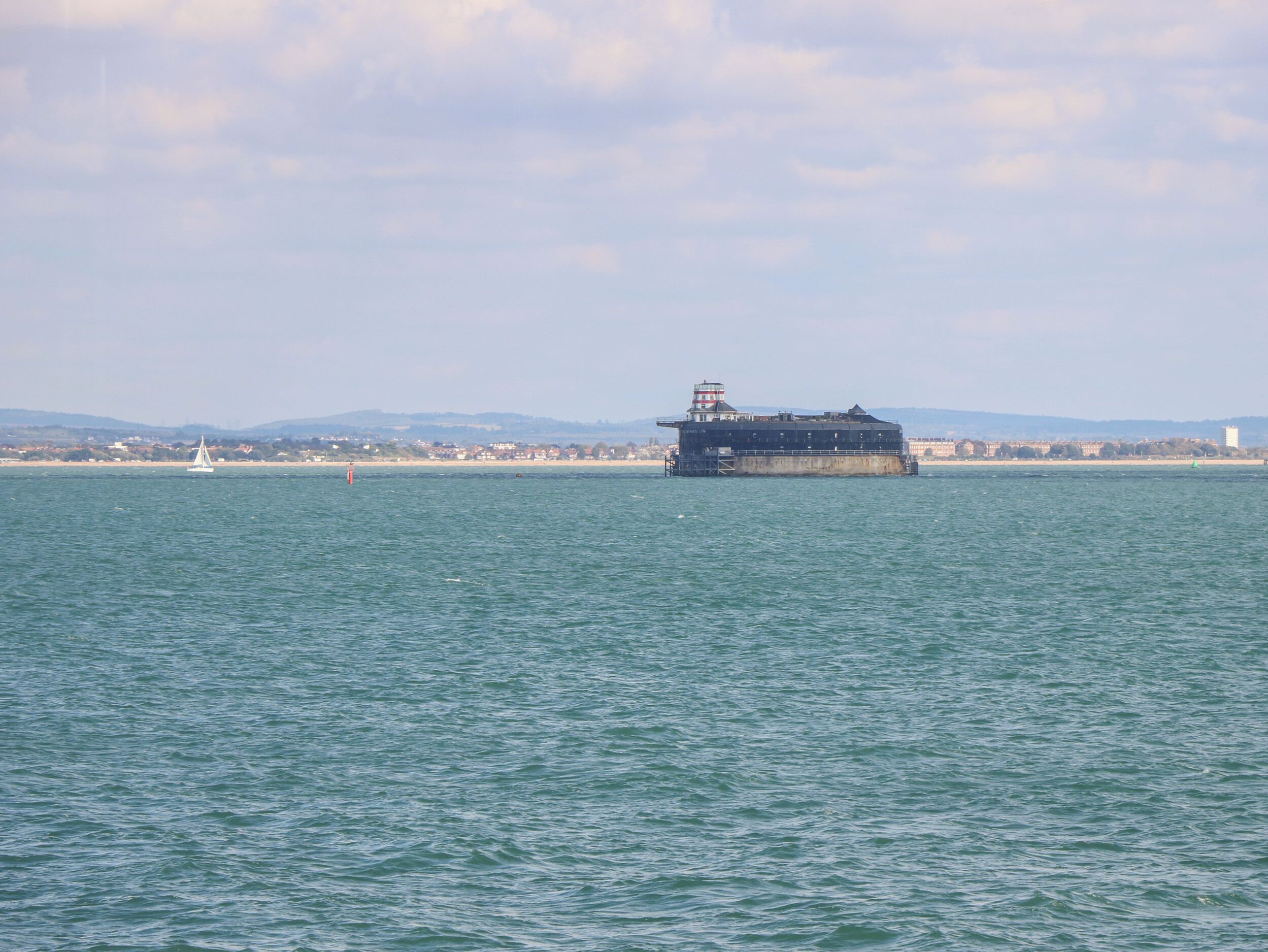 Ein großes Schiff liegt in ruhigem Wasser vor einer Stadtkulisse.