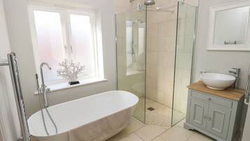 Ein modernes Badezimmer mit einer freistehenden Badewanne, einer Duschkabine und einem Waschtisch.