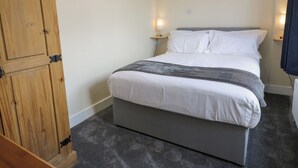 Un dormitorio con una cama, un armario de madera y dos lámparas de noche.