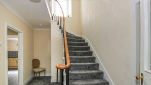 Una escalera alfombrada con barandas de madera y una puerta blanca al final.