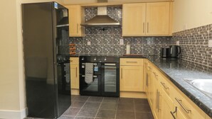 Una cocina moderna con un refrigerador negro, horno doble y salpicadero de azulejos.