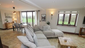 A spacious living room with a large sectional sofa, a wooden coffee table, and a dining area with a table and chairs.