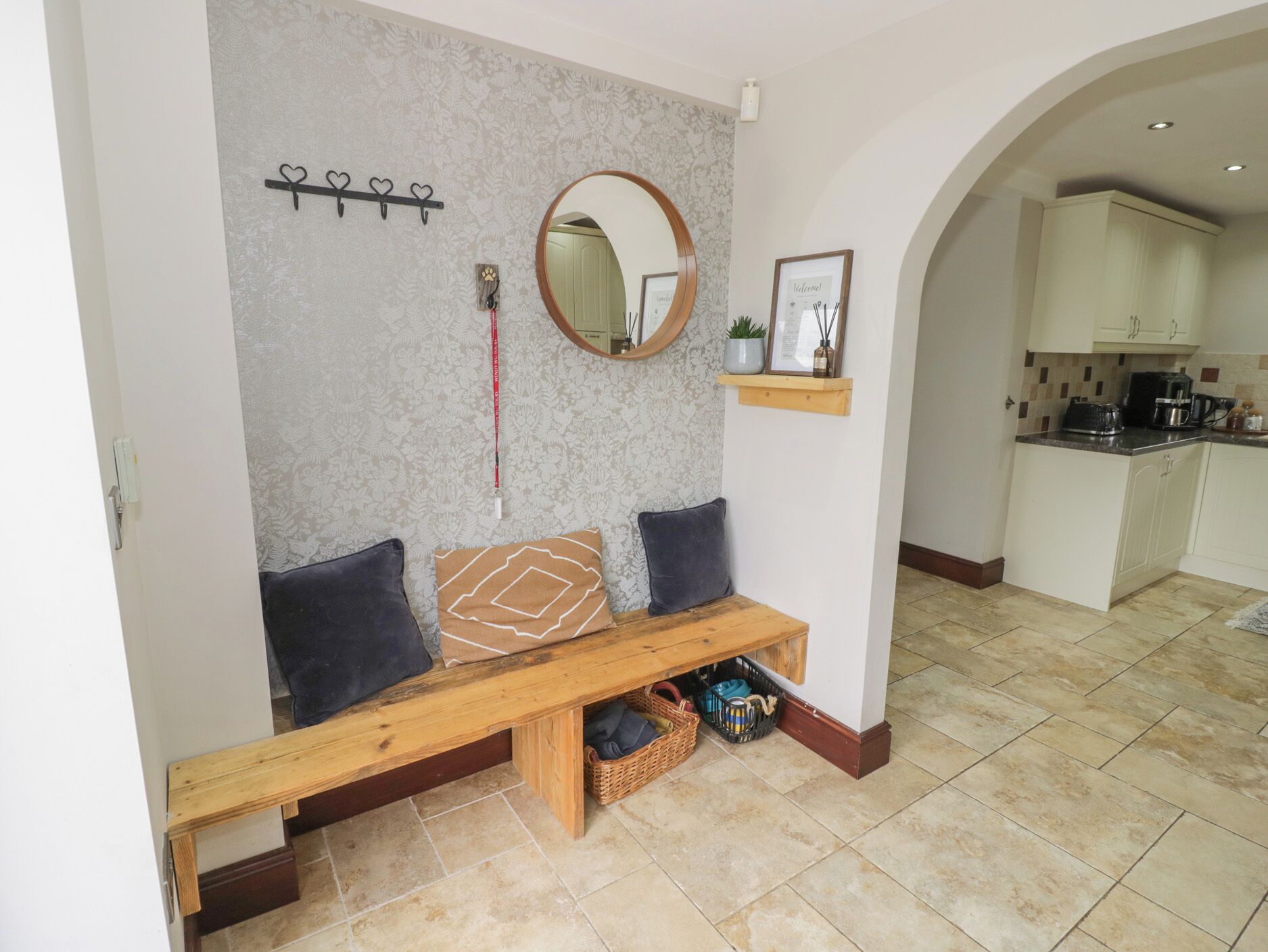 A cozy sitting area with a bench, a mirror, and a shelf with a plant.