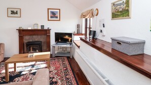 A living room with a fireplace, a television, a sofa, and a coffee table. - The Dairy (Liskeard)