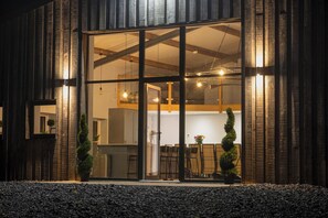 A modern building with large glass windows, a wooden exterior, and a visible interior with a dining area. - The Old Sheep House (Settle)