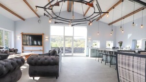Amplia sala de estar con un sofá grande, un televisor y una zona de cocina con taburetes de bar.