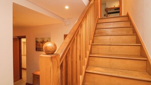 A wooden staircase with a wooden handrail and a wooden ball finial at the top. - Blue Hill House (Ambleside)