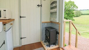 A compact kitchen with a wood-burning stove, a microwave, and a small refrigerator.
