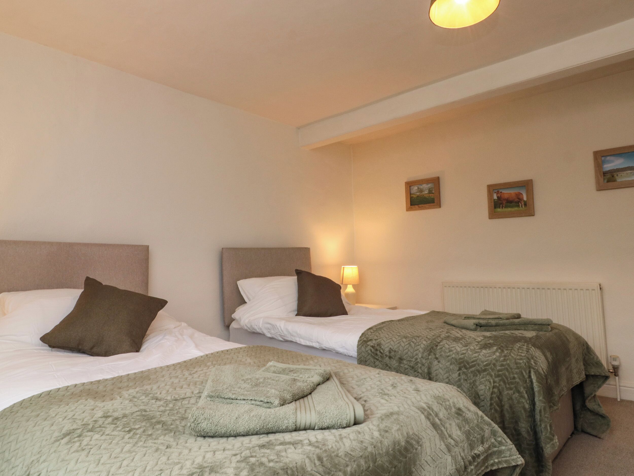 A hotel room with two beds, a radiator, and a lamp.