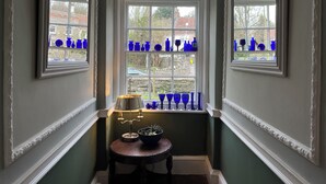 Ein Zimmer mit Erkerfenster und darin blaues Glaswaren-Stillleben.